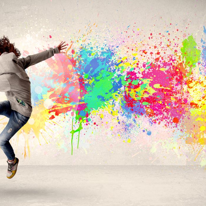 Happy teenager jumping with colorful ink splatter on urban background concept