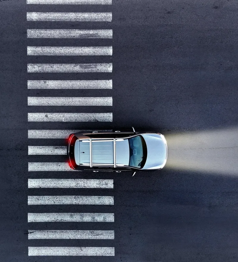 Aerial.,A,Car,With,Its,Headlights,On,Drives,Over,A