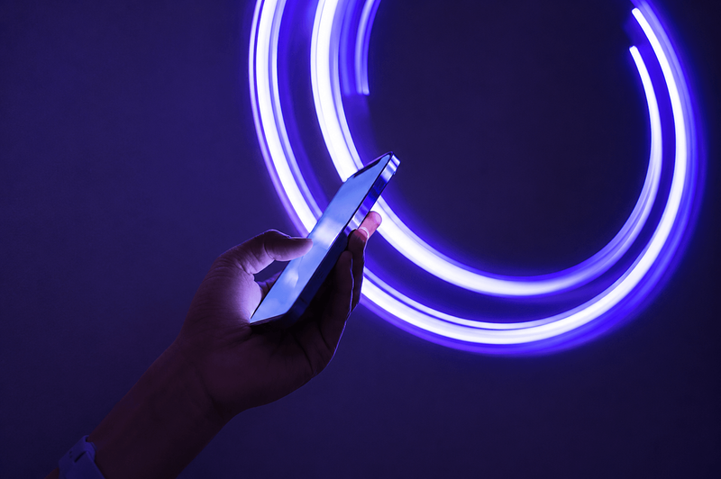 hand holding mobile phone on neon abstract background