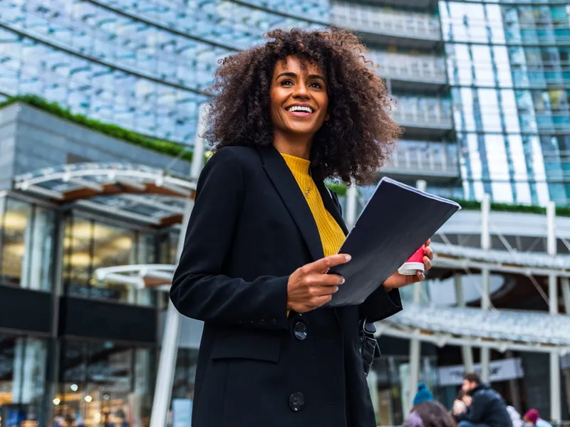 woman holds document case and cup with hot beverage