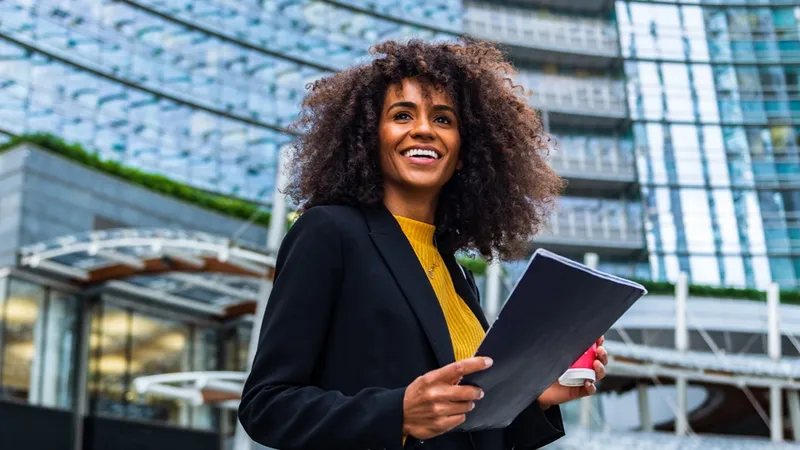 woman holds document case and cup with hot beverage