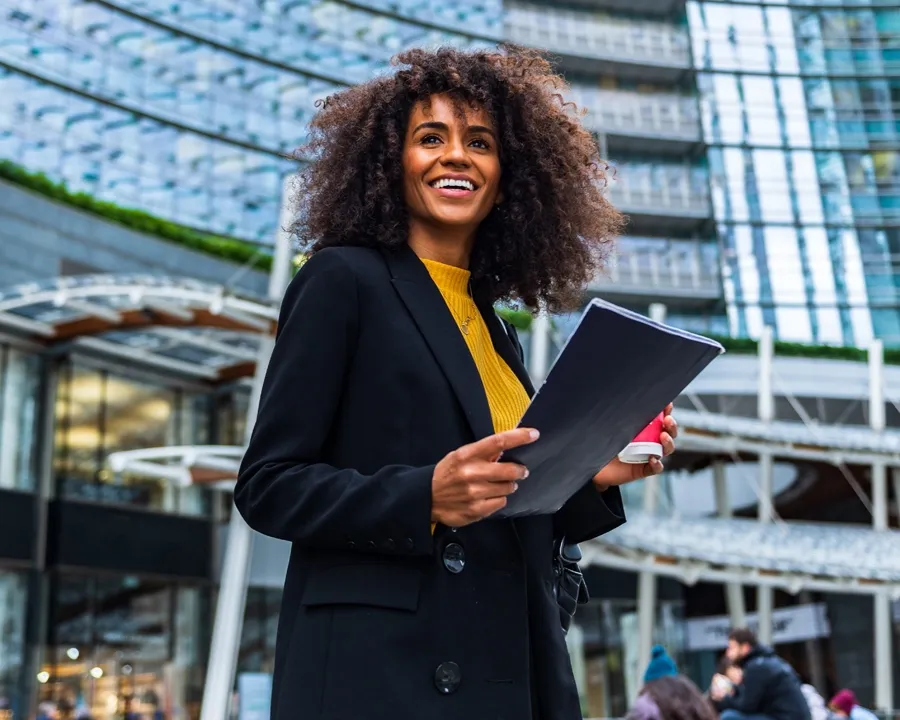 woman holds document case and cup with hot beverage
