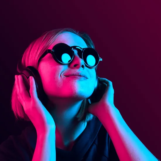 Happy pretty woman with headphones listening to music over red neon background at studio.