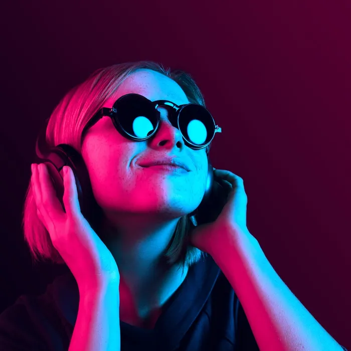 Happy pretty woman with headphones listening to music over red neon background at studio.