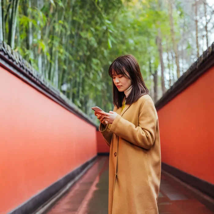 A woman standing in a walkway looking at her phone