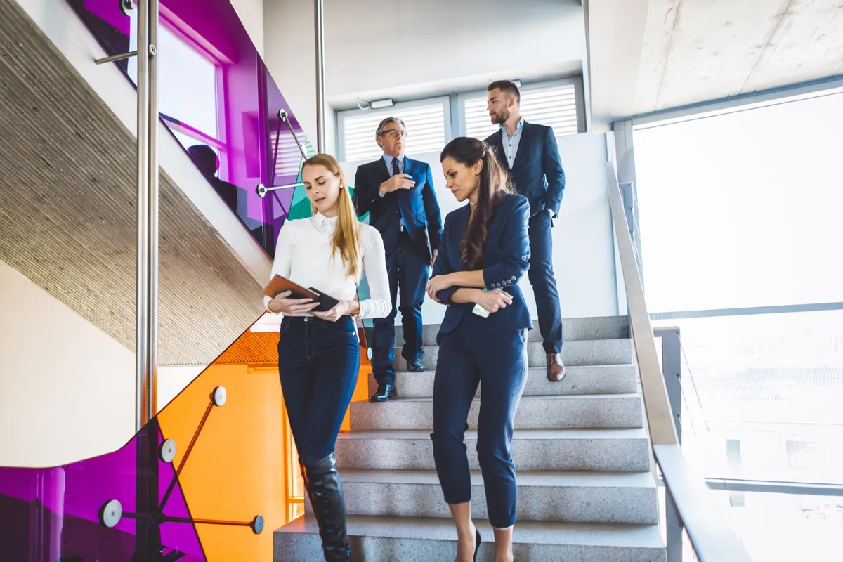 A group of business people walking down the stairs, all wearing elegant business clothes and holding some documents while walking, hard work always pays off, coworkers manage business and finance industry.