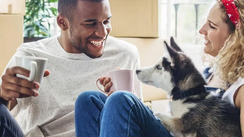 A couple sitting laughing with a dog