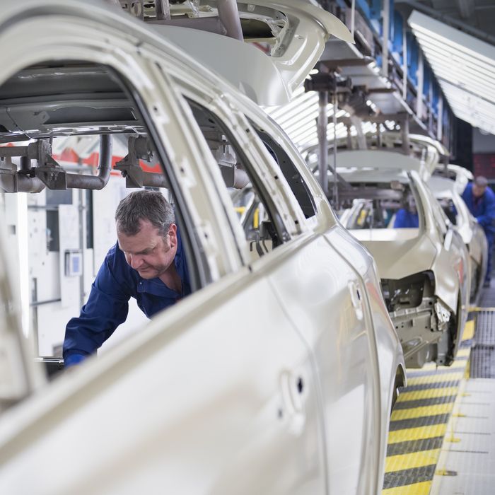 Worker fitting sound proofing to car in car factory