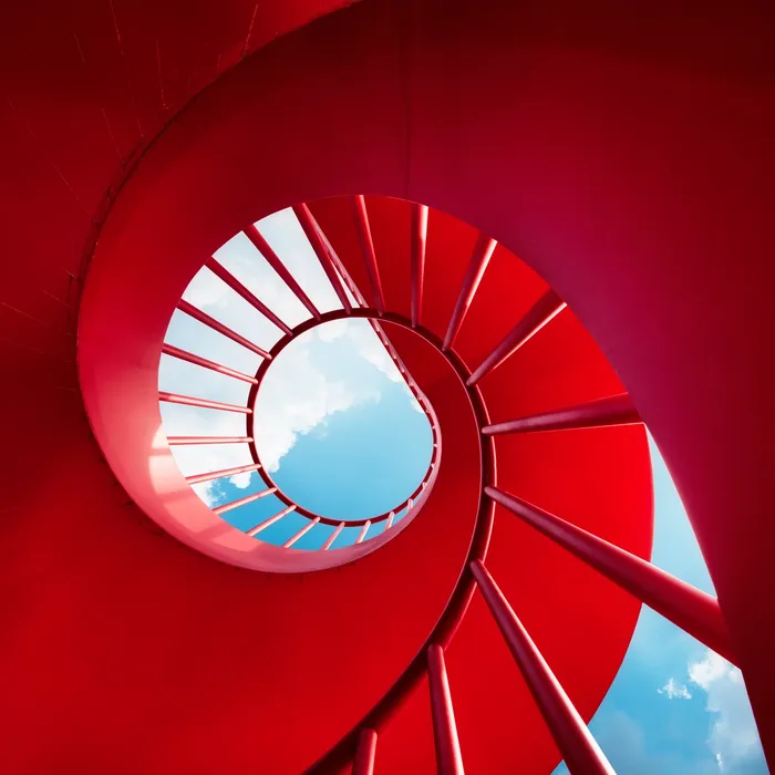 Red spiral staircase against skyColorful Human