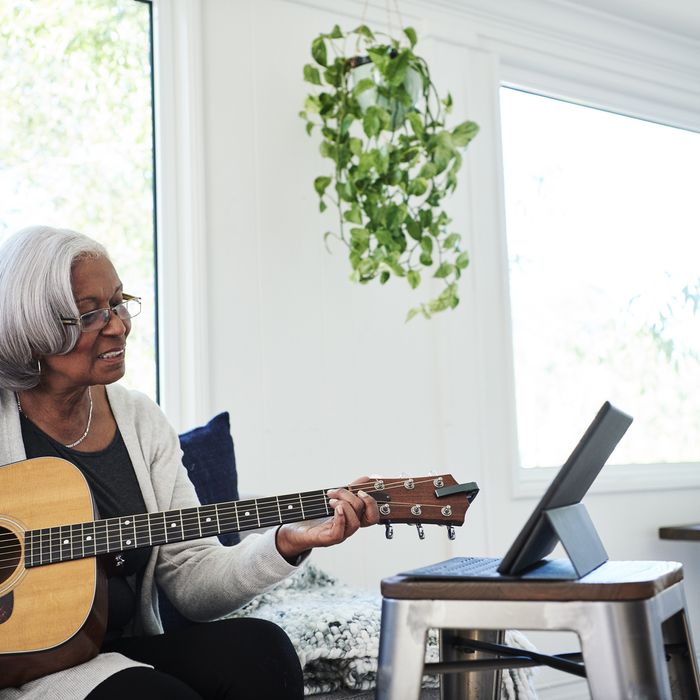 Senior woman playing guitar at home