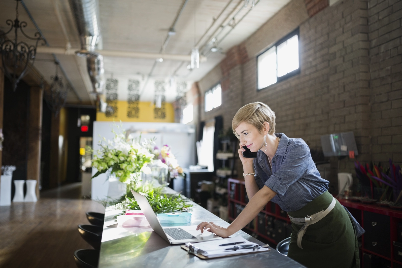 Florist arbeitet am Laptop im Blumenladen