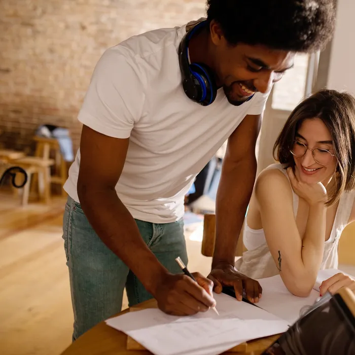 Standing man is showing a woman something on paper