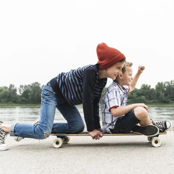 Happy boys on skateboard at the riverside