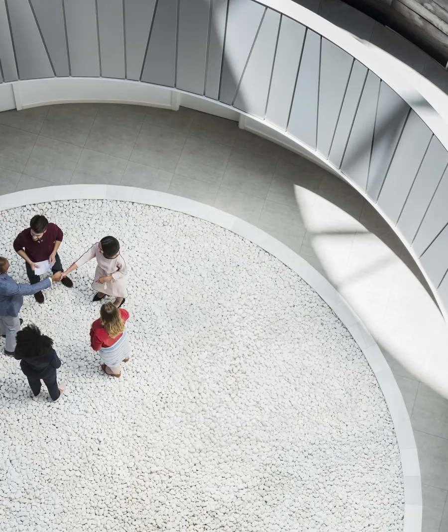 View from above business people handshaking in round modern office atrium courtyard
